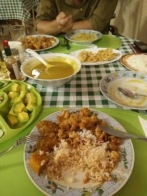 Tafel gedekt met meerdere borden eten zoals rijst, gefrituurde gerechten, avocado en soep op een groen-wit geruite tafel in Cuba