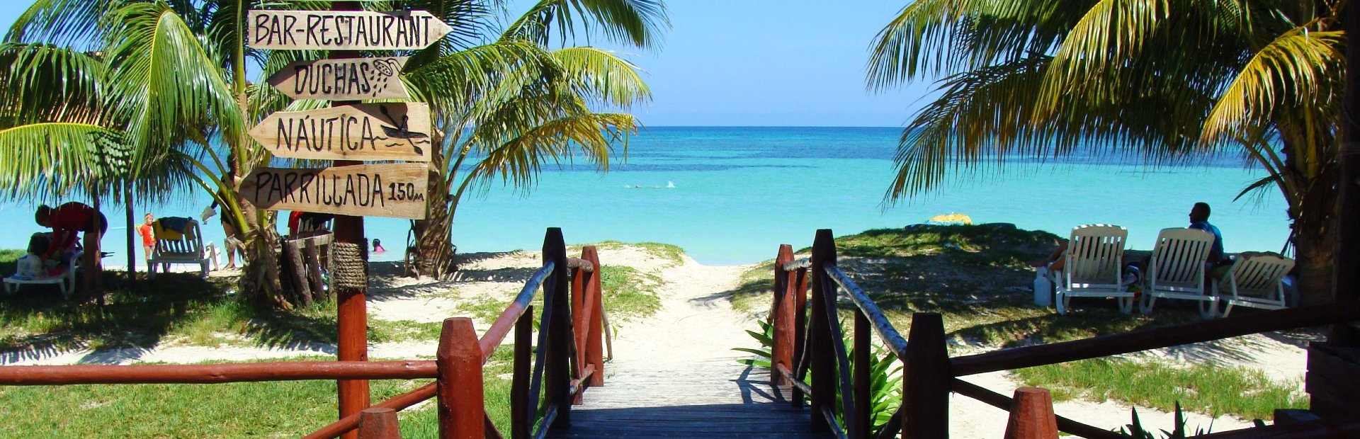 Houten pad naar tropisch strand met palmbomen en helderblauwe zee in Varadero Cuba