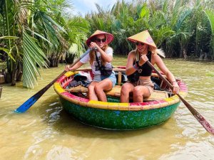 twee vrouwen met een typisch Vietnamees punthoedje op varen door het water in een kleine Vietnamese boot