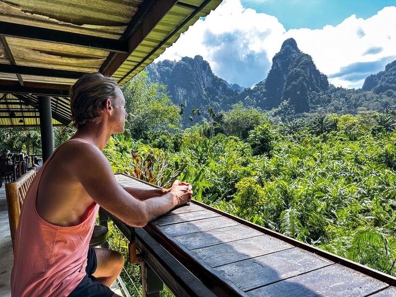 Reiziger kijkt uit over de jungle en karstbergen van Khao Sok Thailand vanaf een overdekt terras