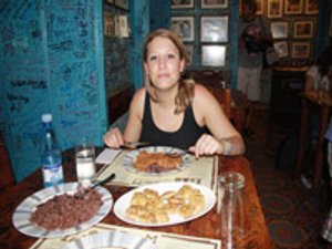 Jonge vrouw die aan tafel in een restaurant in Havana, Cuba een maaltijd eet en in de camera kijkt