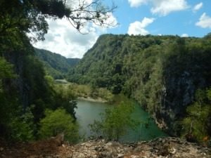 Brede groene rivier stroomt tussen steile met bomen begroeide bergen onder een bewolkte lucht in Cuba