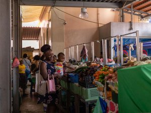 Lachende zwarte vrouw houdt een baby vast die reikt naar verse groenten op een overdekte markt