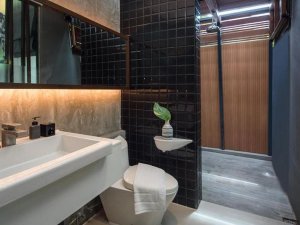 Modern ingerichte badkamer met zwart tegelwerk, inloopdouche en wastafel met spiegelwand.