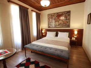 Hotelkamer in Albanië met groot bed, wandtapijt met jachttafereel en een rijk bewerkt houten plafond