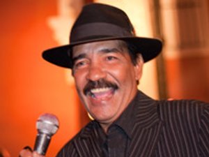 Lachende man met donkere fedora en colbert houdt een microfoon vast tijdens optreden in Havana Cuba