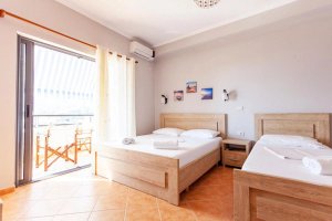 Hotelkamer aan de Albanese Rivièra met twee houten bedden, balkon en uitzicht naar buiten