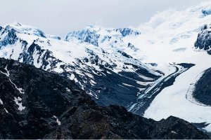 Besneeuwde bergen en gletsjers rijzen boven donkere rotsachtige hellingen op het Zuidereiland in Nieuw-Zeeland