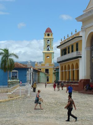 Kasseienplein in Trinidad met kleurrijke koloniale gebouwen, een gele klokkentoren en mensen die rondlopen in Cuba