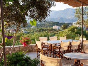Terras met houten stoelen en tafels aan de Albanese Rivièra met uitzicht op groene heuvels en bergen