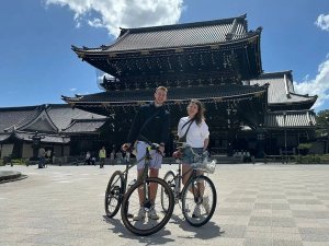 Twee mensen met de fiets staan voor een tempel in Kyoto