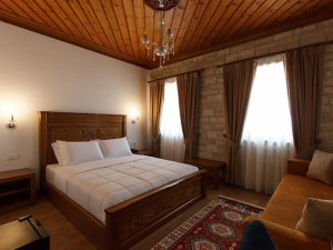 Hotelkamer in Gjirokastër in Albanië met groot houten bed, sierlijk houten plafond, kroonluchter en zithoek