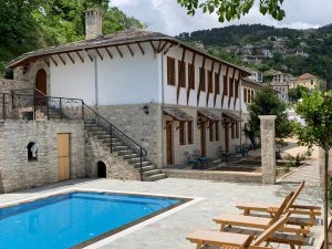 Traditioneel guesthouse in Gjirokastër in Albanië met zwembad, ligbedden en uitzicht op een heuvel met huizen