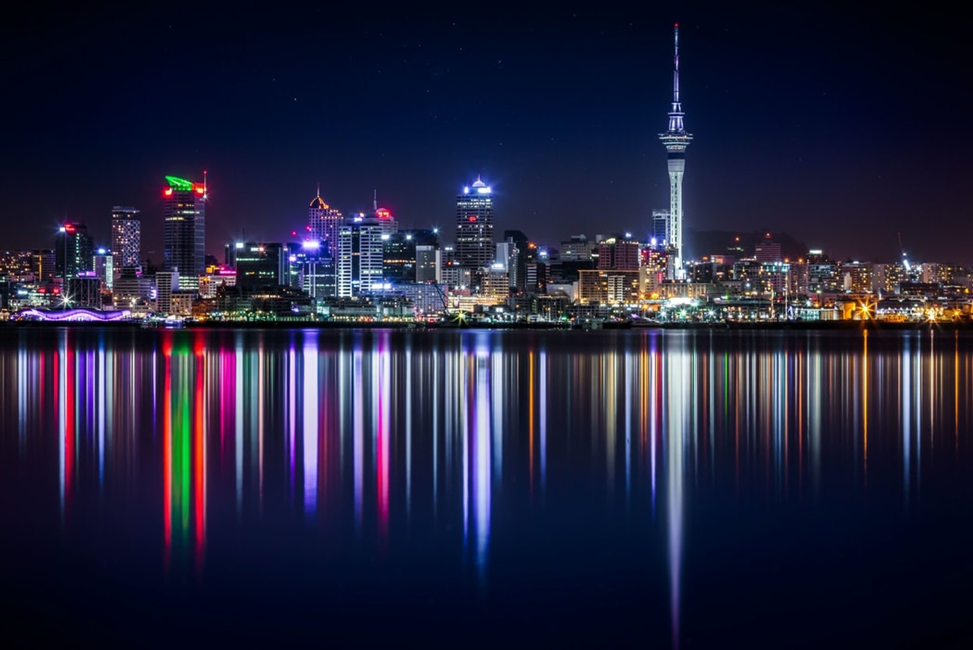 Levendige stads skyline bij nacht met lichtreflecties in het water aan de kust