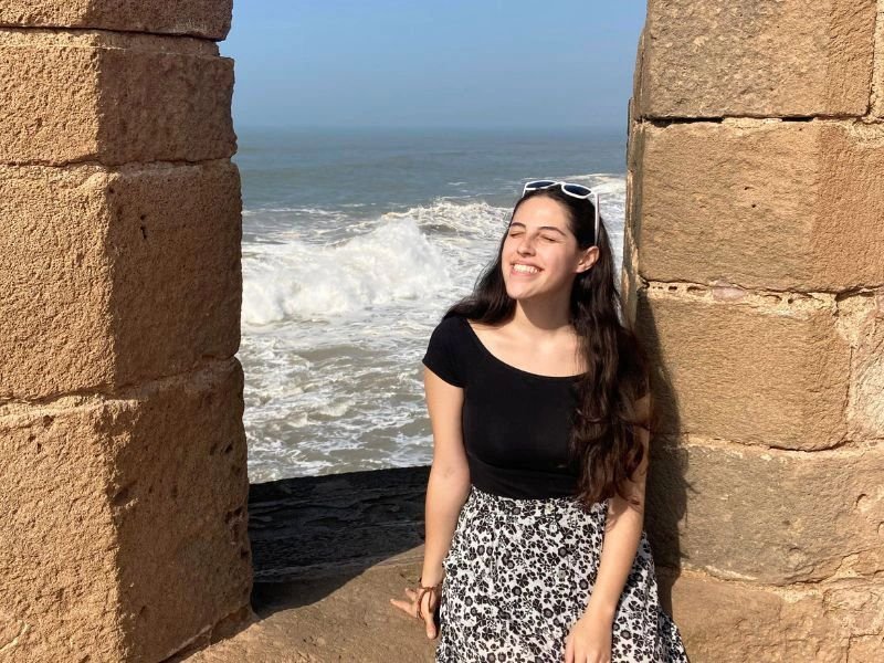 vrouw zit in een inham met achter haar de zee in Essaouira