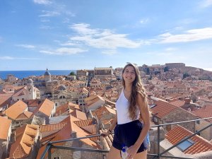 Lachende jonge vrouw met uitzicht op stad met rode daken en zee in Kroatië
