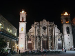 Verlichte sierlijke kerk met twee torens en mensen die eten op het plein in Trinidad Cuba