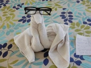 Handdoekfiguur met zwarte bril op een bed met patroon in Cuba