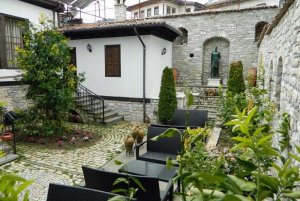 Sfeervolle binnenplaats met stenen muren, zitgedeelte en groen bij traditioneel huis in Berat, Albanië