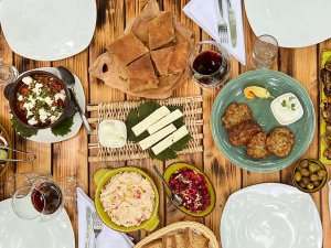 Bovenaanzicht van houten tafel rijkelijk gevuld met traditionele mediterrane gerechten, hartige taarten, kaas, salades en warme gerechten met rode wijn in Berat, Albanië