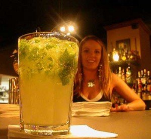 Verfrissende cocktail met munt op een bar in Havana, Cuba met een lachende vrouwelijke bartender op de achtergrond