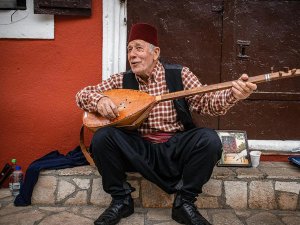 Lachende oude man met rode fez speelt een snaarinstrument in Kroatië