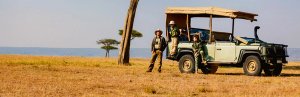 Drie mensen bij een safarivoertuig in een droog savannelandschap in Zuid-Afrika