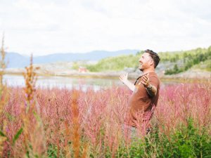 Man staat lachend in het midden van de natuur met een lentezon op zijn gezicht.