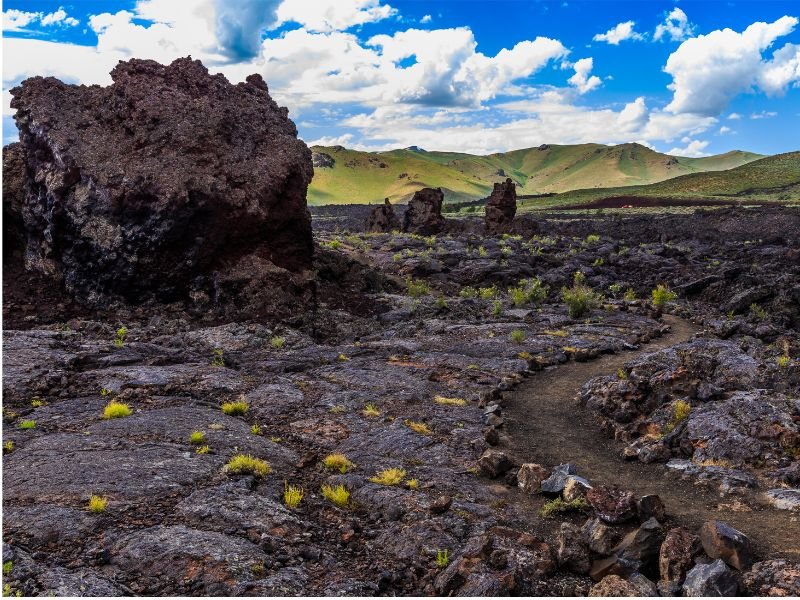 Lanschap van lava met op de achtergrond groene heuvels