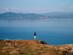 Wandelaar op een klif bij het Ohridmeer in Noord-Macedonië met uitzicht op een uitgestrekt blauw meer en bergen in de verte