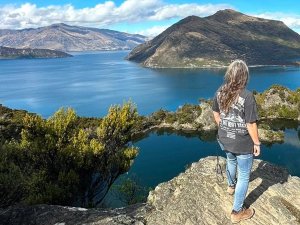 Vrouw staat op een rotsachtig uitkijkpunt en bewondert een uitgestrekt bergmeer in een bergachtig natuurgebied