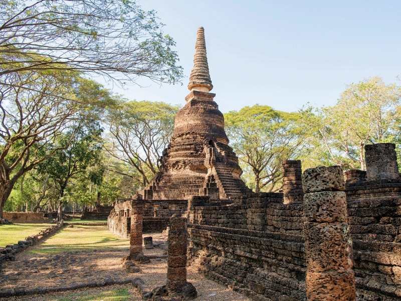 Oude, verweerde stoepa in een groene, bosrijke omgeving in Sukhothai.