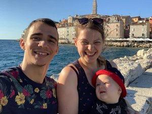 Lachend gezin van drie maakt een selfie aan zee met een sfeervol kustplaatsje op de achtergrond in Kroatië