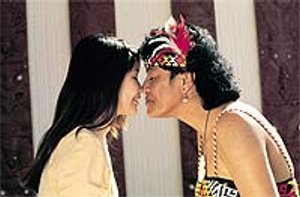 Twee mensen, waarvan één in traditionele Māori kleding, raken elkaars voorhoofd en neus aan tijdens een hongi begroeting in een culturele setting in Nieuw-Zeeland